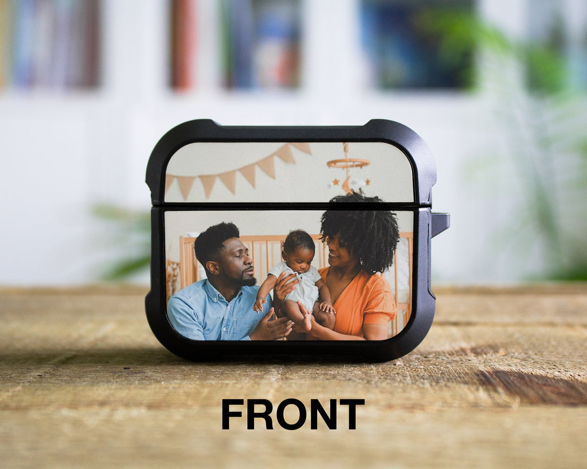 A black AirPods Pro 1st 2nd or 3rd Gen case with a custom printed photo of a family on the front, displayed on a wooden surface with a blurred indoor background. The word 'FRONT' is printed below the case.