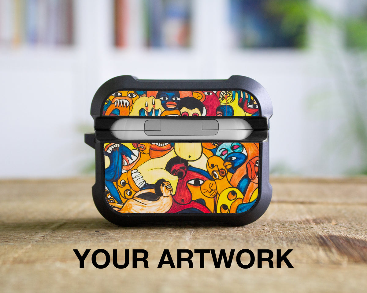 A black protective AirPods Pro 1st 2nd or 3rd Gen case with a colorful cartoon-style illustration of faces and abstract shapes, shown on a wooden surface with a blurred indoor background. The text 'YOUR ARTWORK' is printed below the case.