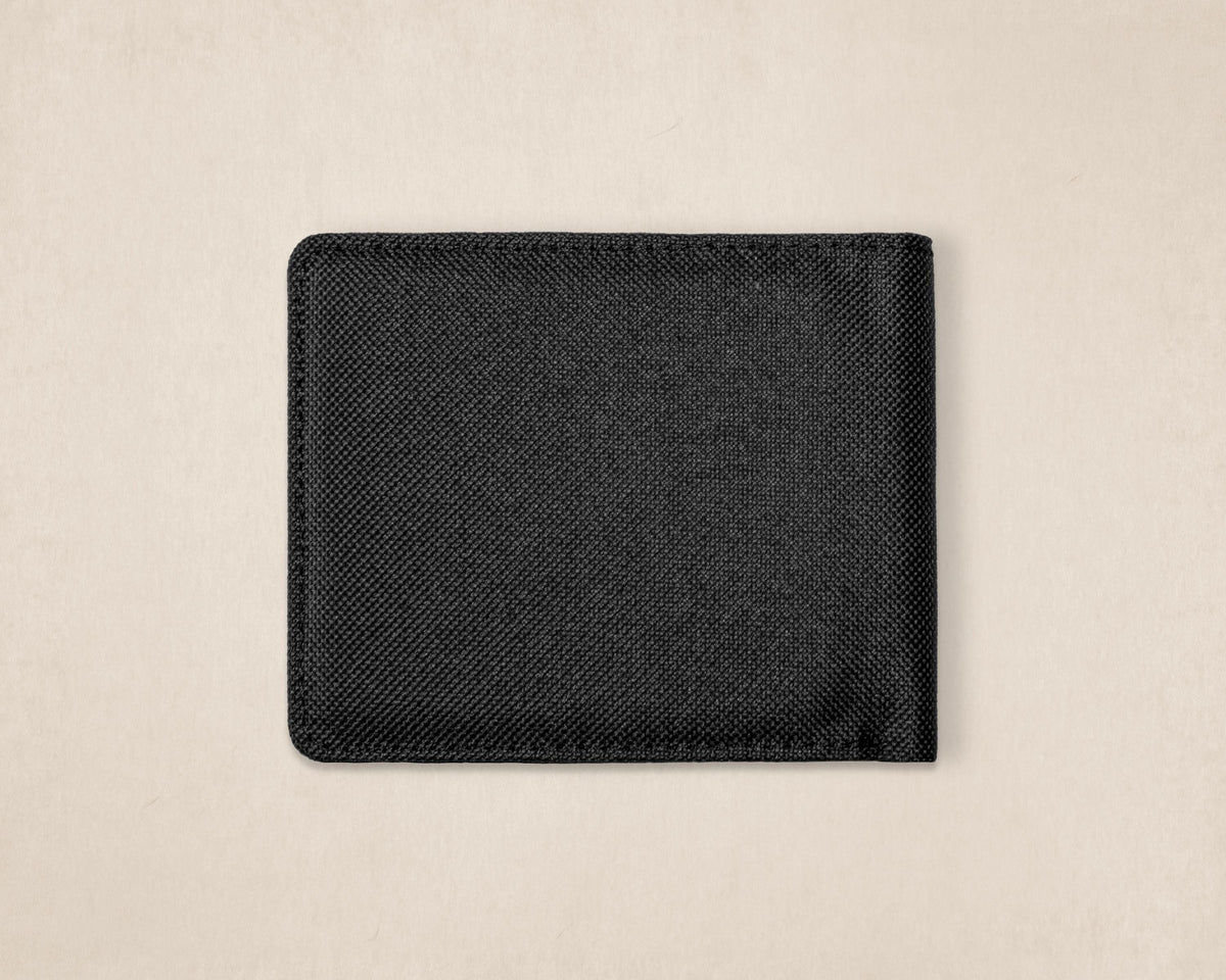 A black canvas fabric bifold wallet with rounded corners, shown closed on a light beige textured background.
