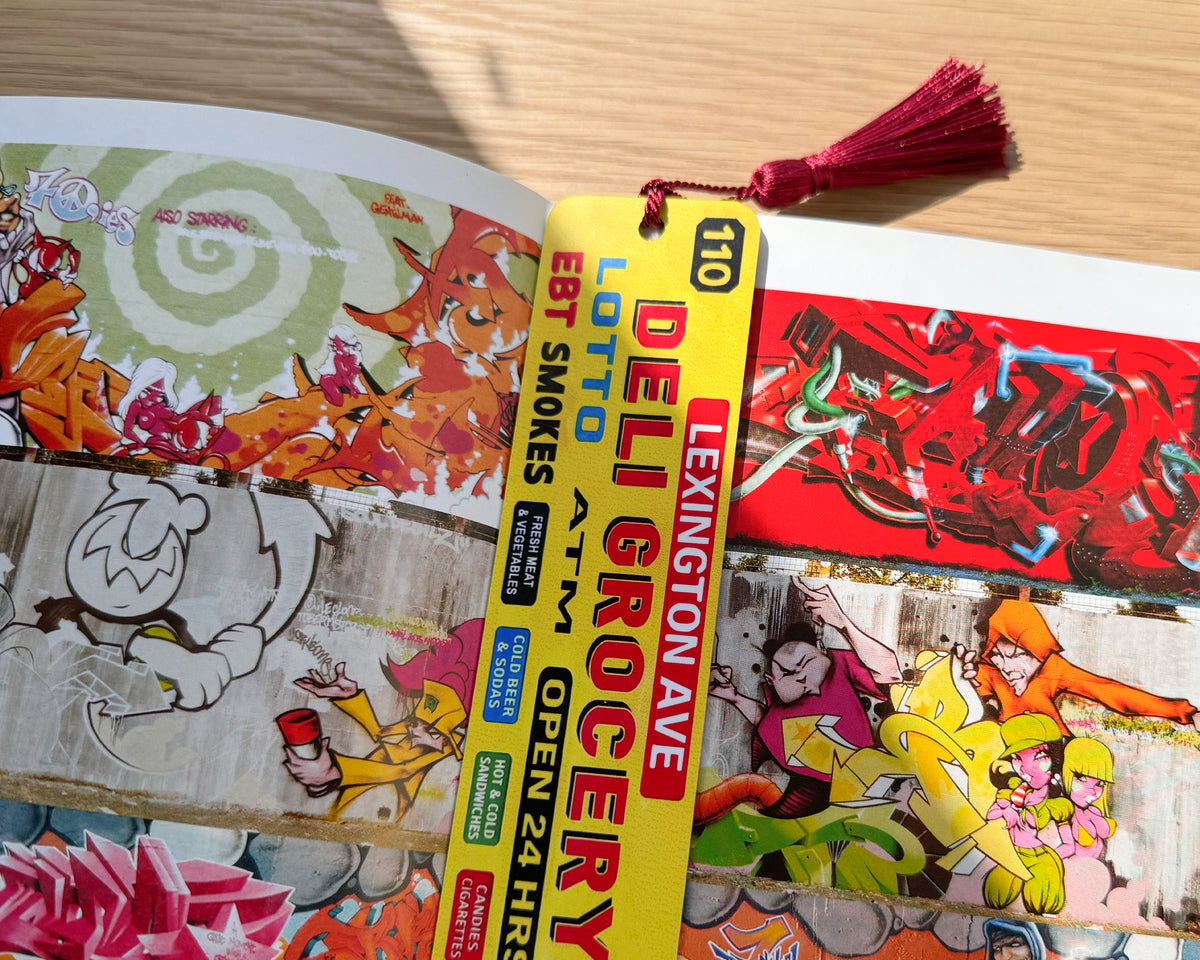 Urban-themed aluminum bookmark placed inside a graffiti art book. Slim metal design fits comfortably between pages without bulk. Creative gift idea for readers, art lovers, students, and anyone who enjoys bold city-inspired book accessories.