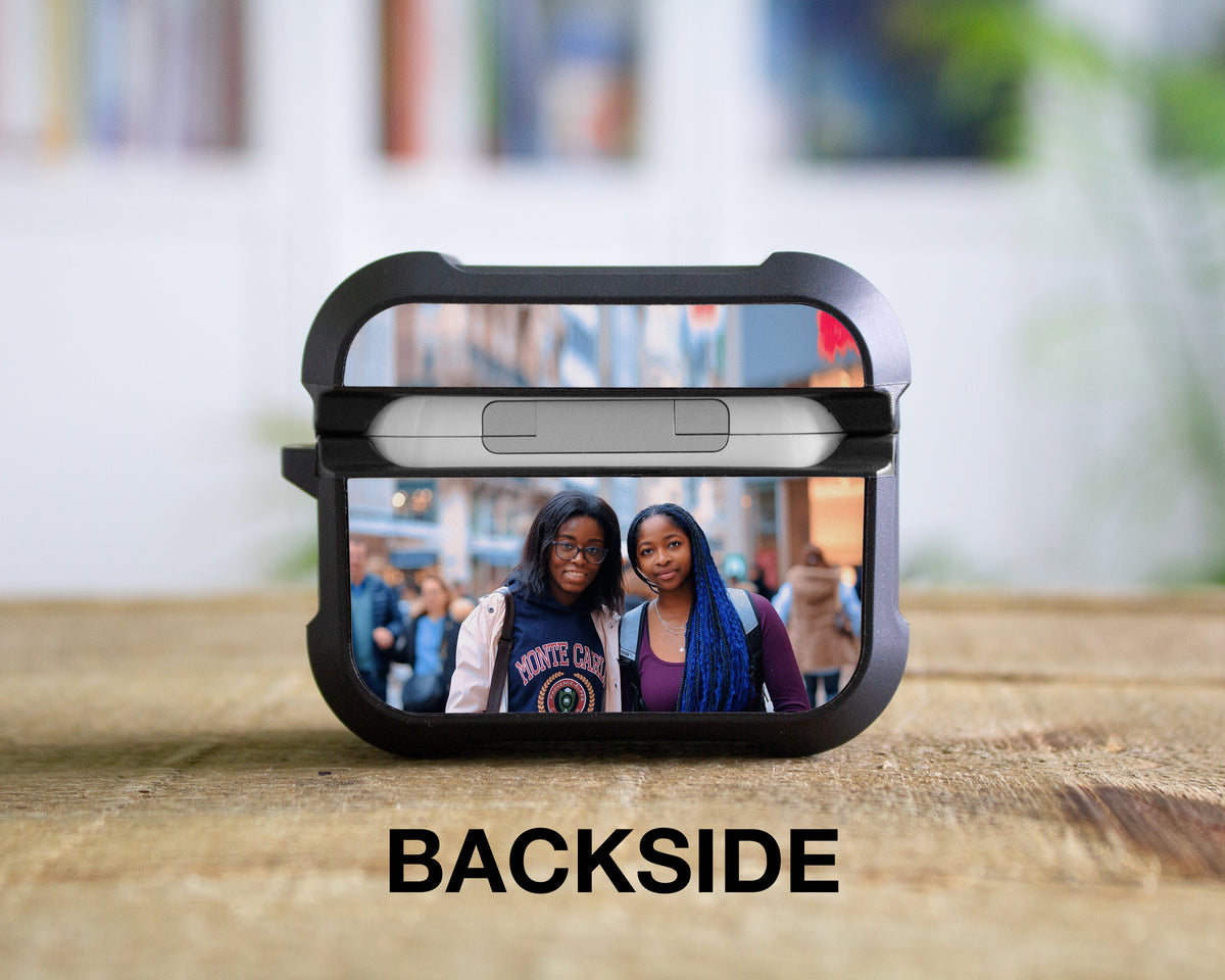 A black protectiveAirPods Pro 1st 2nd or 3rd Gen case for wireless earbuds sits open on a wooden surface, with a printed photo of two women reflected inside the case. The word 'BACKSIDE' is printed below in bold black letters.
