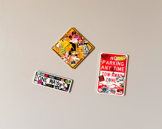Three rectangular and diamond-shaped fridge magnets with colorful graffiti-style designs and traffic-themed text, displayed on a plain beige background.