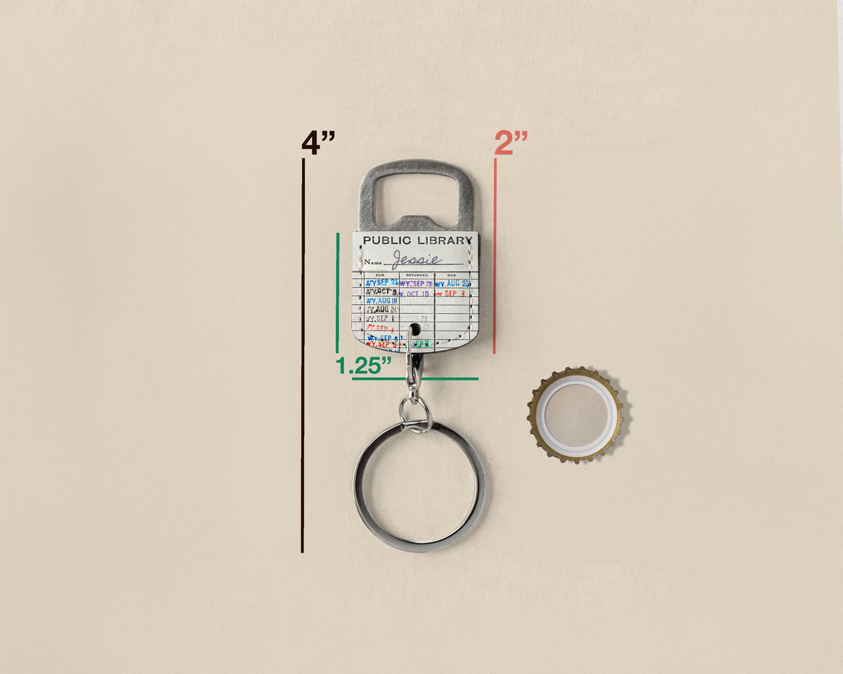 A metal bottle opener keychain with a library card insert, shown on a beige background with red and green dimension lines indicating 4 inches tall, 2 inches wide, and 1.25 inches thick, plus a separate bottle cap to the right.