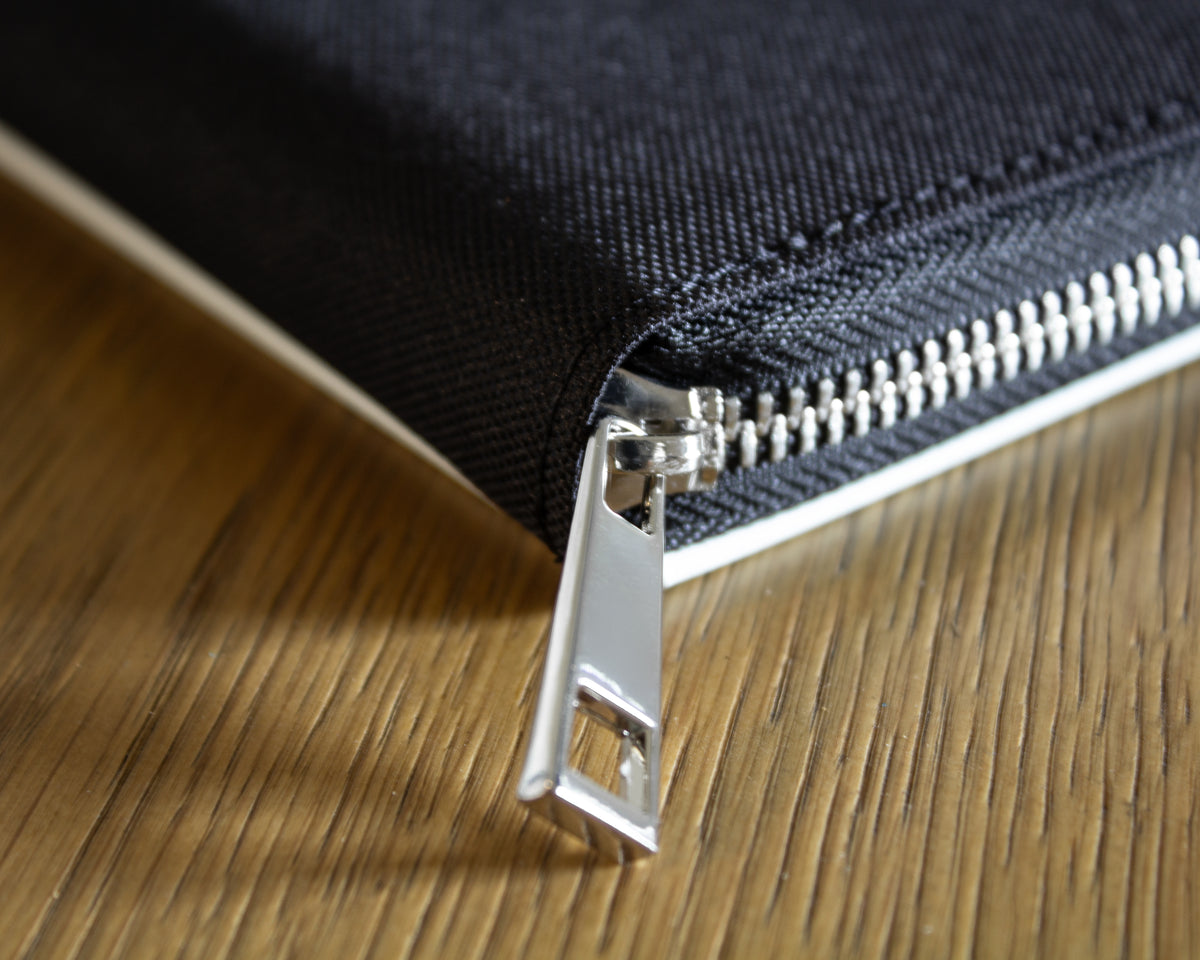 Close-up of a zipper on a black canvas fabric on a wood table background