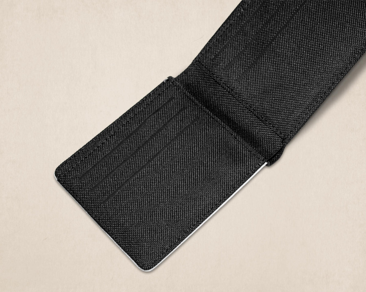 A close-up of a black canvas  cardholder or wallet with multiple card slots, shown partially open on a light beige background.