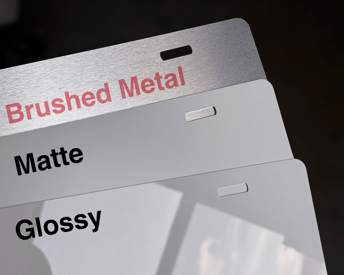 Three brushed metal sample panels stacked slightly offset, labeled 'Brushed Metal,' 'Matte,' and 'Glossy' in black and red text, with a dark background.