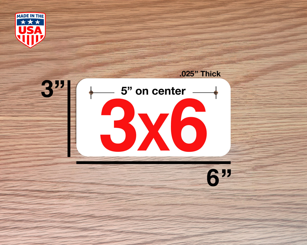 A white rectangular e-Bike license plate with large red '3x6' text, shown on a wood-grain background with dimension labels indicating 3 by 6 inches and .025 inch thickness.