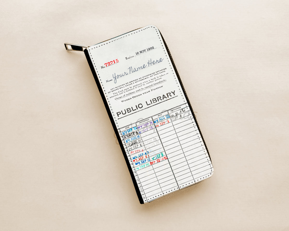 A zip-around wallet styled like a vintage library card women's wallet, featuring a white and black design with printed text with a handwritten-style on a cream colored background.