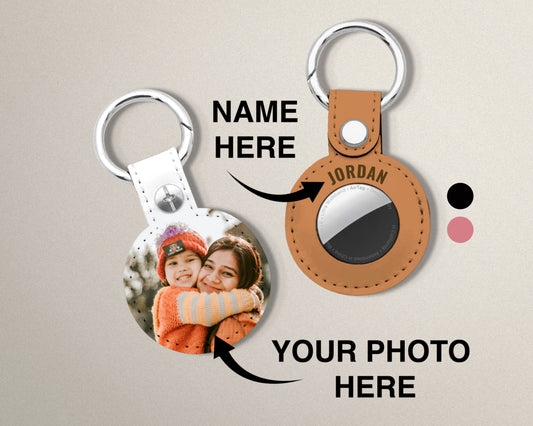 Custom vegan leather keychain for Airtags with a round photo insert and silver key rings, shown alongside a tan version with the name 'JORDAN' printed on it. The image includes placeholder text reading 'NAME HERE' and 'YOUR PHOTO HERE' on a light beige background.