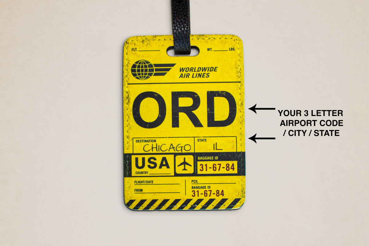 A novelty luggage tag styled like an airport boarding pass, featuring a bright yellow background with black text and graphics. It includes a black hanging strap and printed details such as 'WORLDWIDE AIR LINES', 'ORD', 'CHICAGO', 'IL', and a phone number.