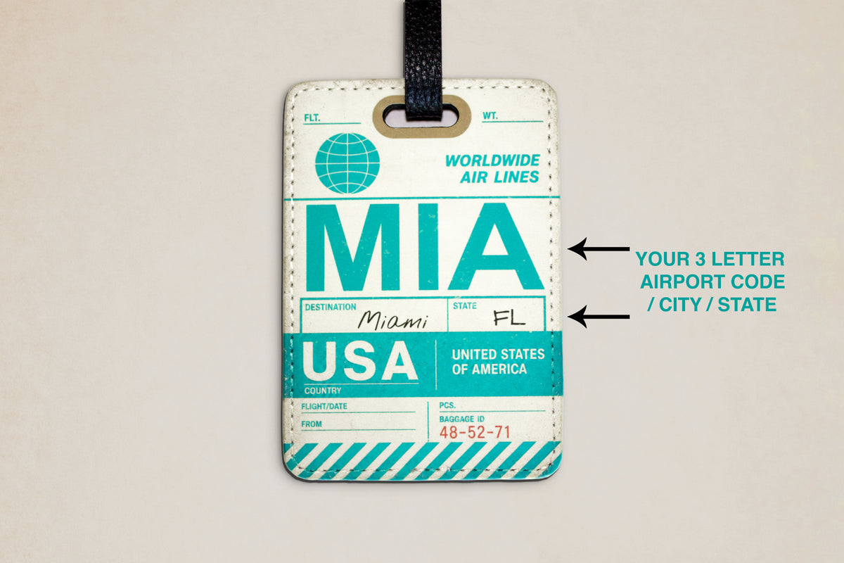 A luggage tag with a black hanging strap, featuring a vintage-style travel ticket design in teal, white, and light blue. The tag includes sample text such as 'WORLDWIDE AIR LINES,' 'DESTINATION Miami,' 'FL,' and 'USA,' with arrows on the right pointing to customizable fields for airport code, city, and state.