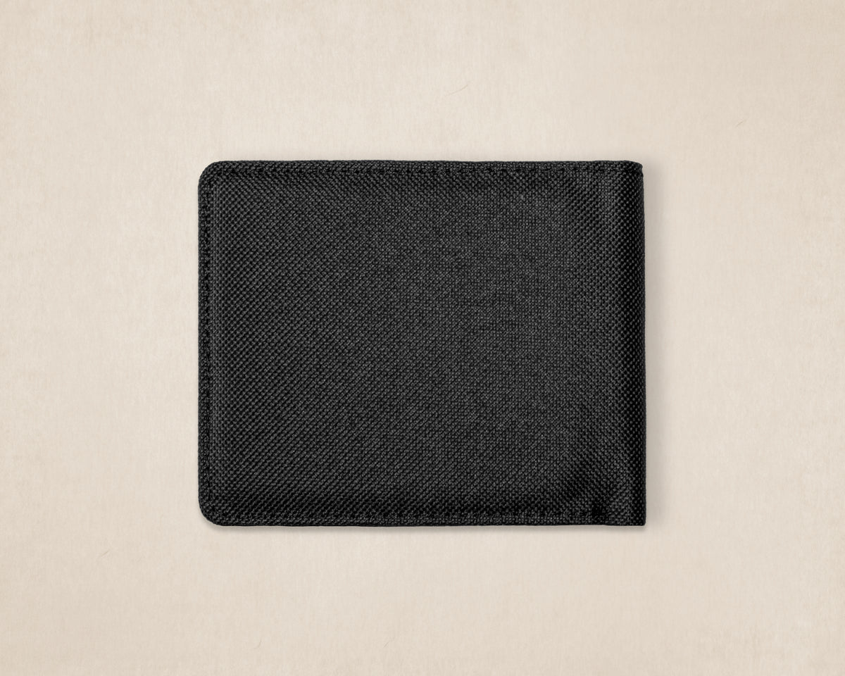 A black textured canvas fabric wallet or card holder with rounded corners, shown flat against a light beige background.