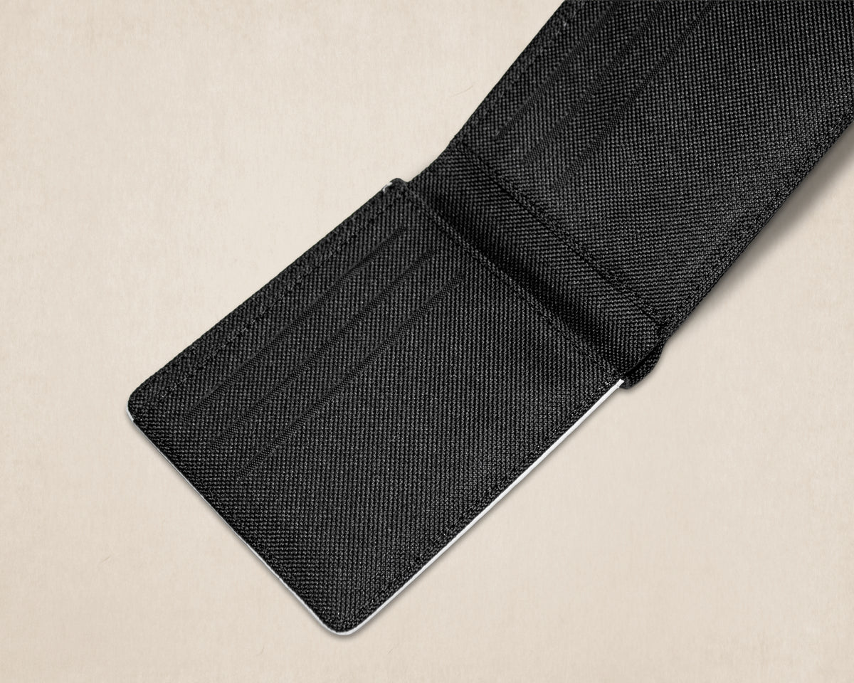 A close-up of a black canvas textured cardholder or wallet with multiple card slots, shown partially open on a light beige background.