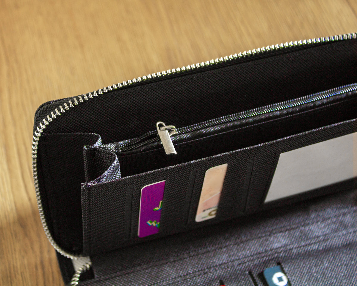 Black canvas women's wallet with card slots on a wooden surface