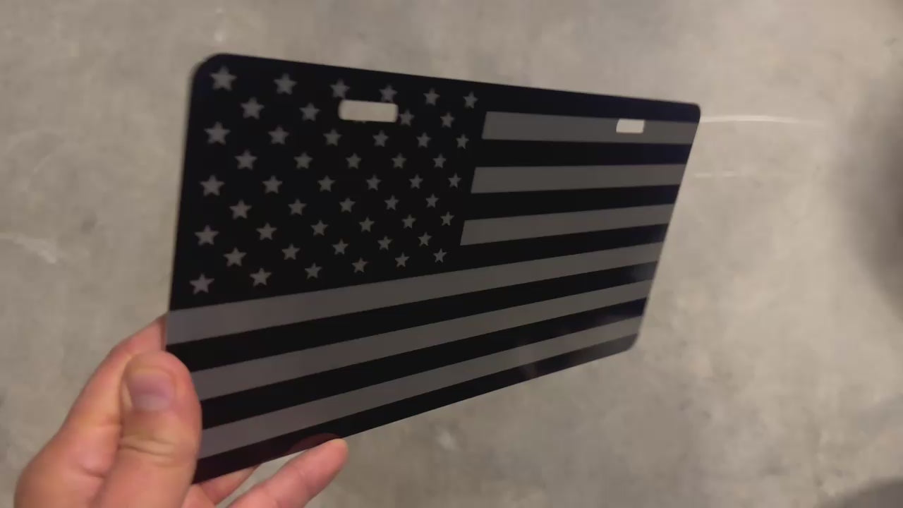 Video of a black and silver brushed metal USA flag lnovelty license plate with a 2 hole mount.