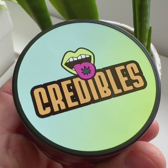 Custom photo herb grinder held in hand with a colorful personalized glossy lid and black zinc-alloy body.